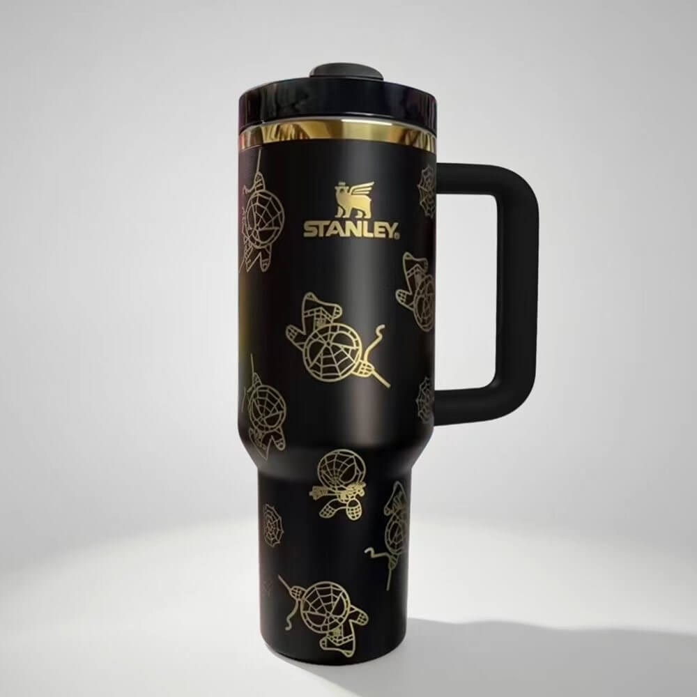 Black Stanley travel mug with gold designs on a white background