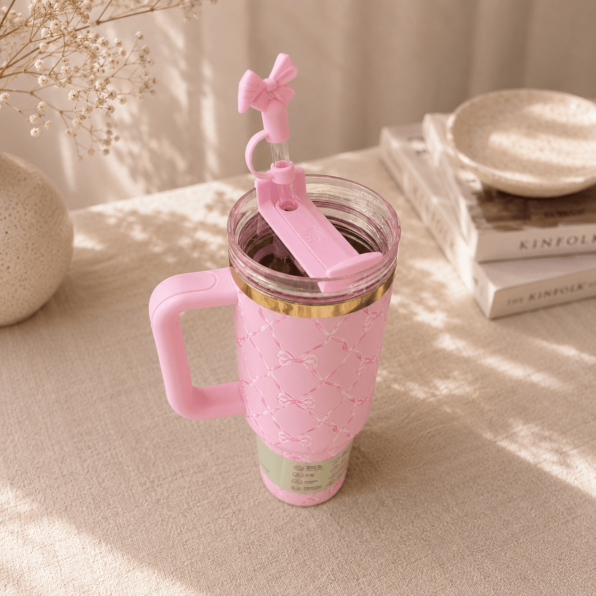 Pink tumbler with handle and straw on a light surface