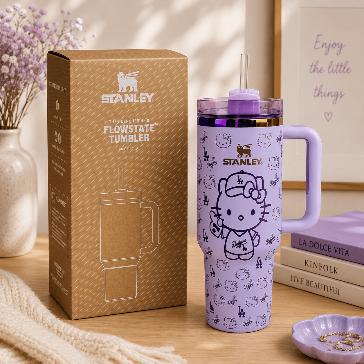 Purple Stanley tumbler with Hello Kitty design next to its packaging on a wooden surface.