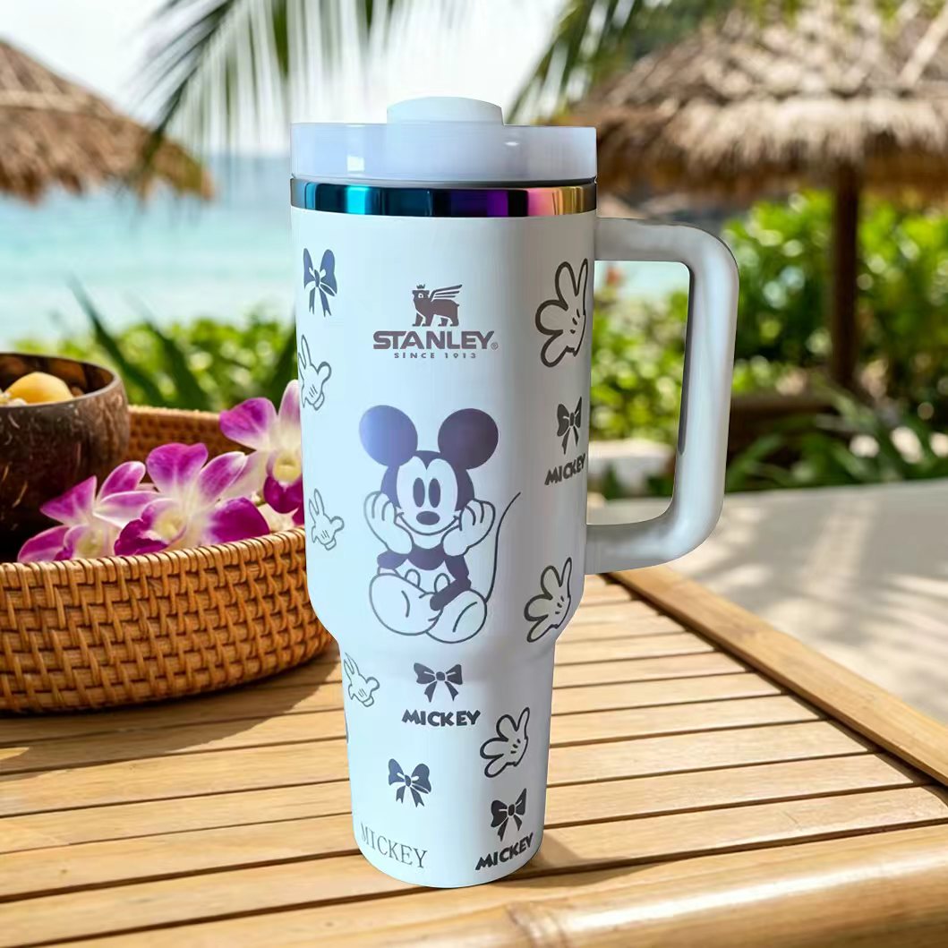 Stanley tumbler with Mickey Mouse design on a wooden table outdoors