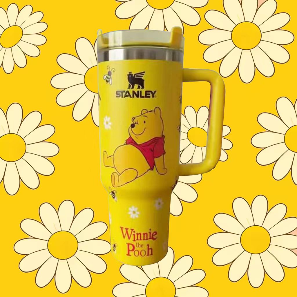Yellow tumbler with Winnie the Pooh design on a yellow background with daisies