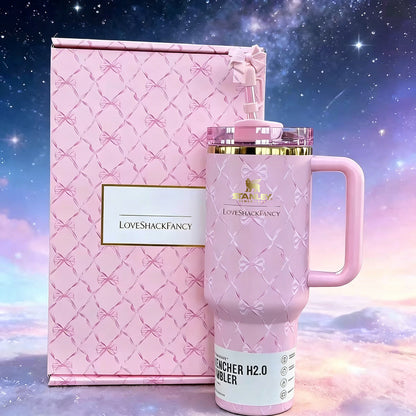 Pink quilted tumbler with handle and matching box against a starry sky background