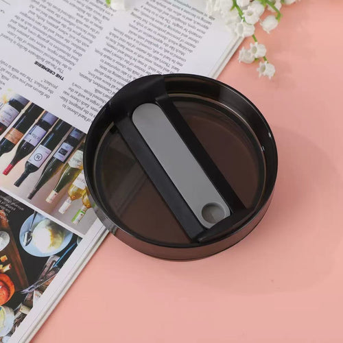Black circular object with a gray center on a pink surface with a magazine underneath