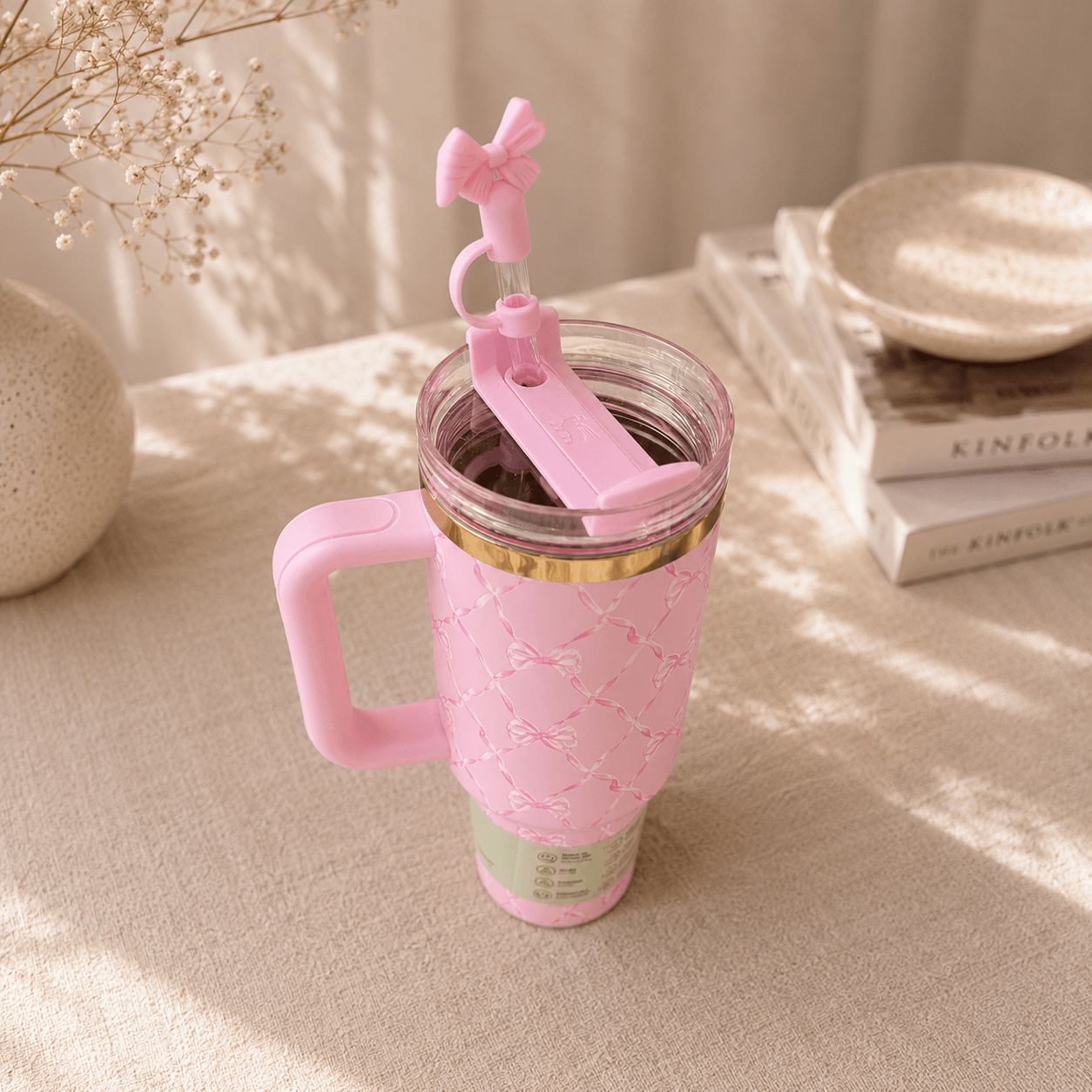 Pink tumbler with handle and straw on a light surface
