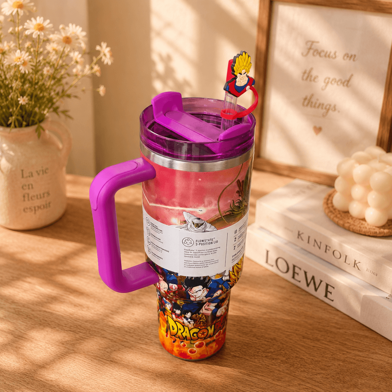 Colorful tumbler with a handle on a wooden surface, surrounded by decor items.
