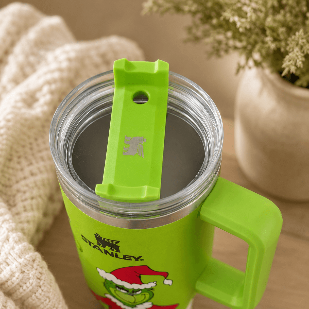 Green Stanley tumbler with a cartoon character on a wooden surface.