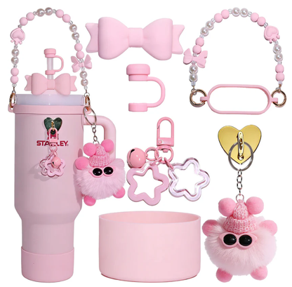 Pastel pink tumbler accessory gift set featuring a silicone cup boot, straw topper, pearl carry strap, handle grip, fluffy pom-pom keychain, and decorative charms.
