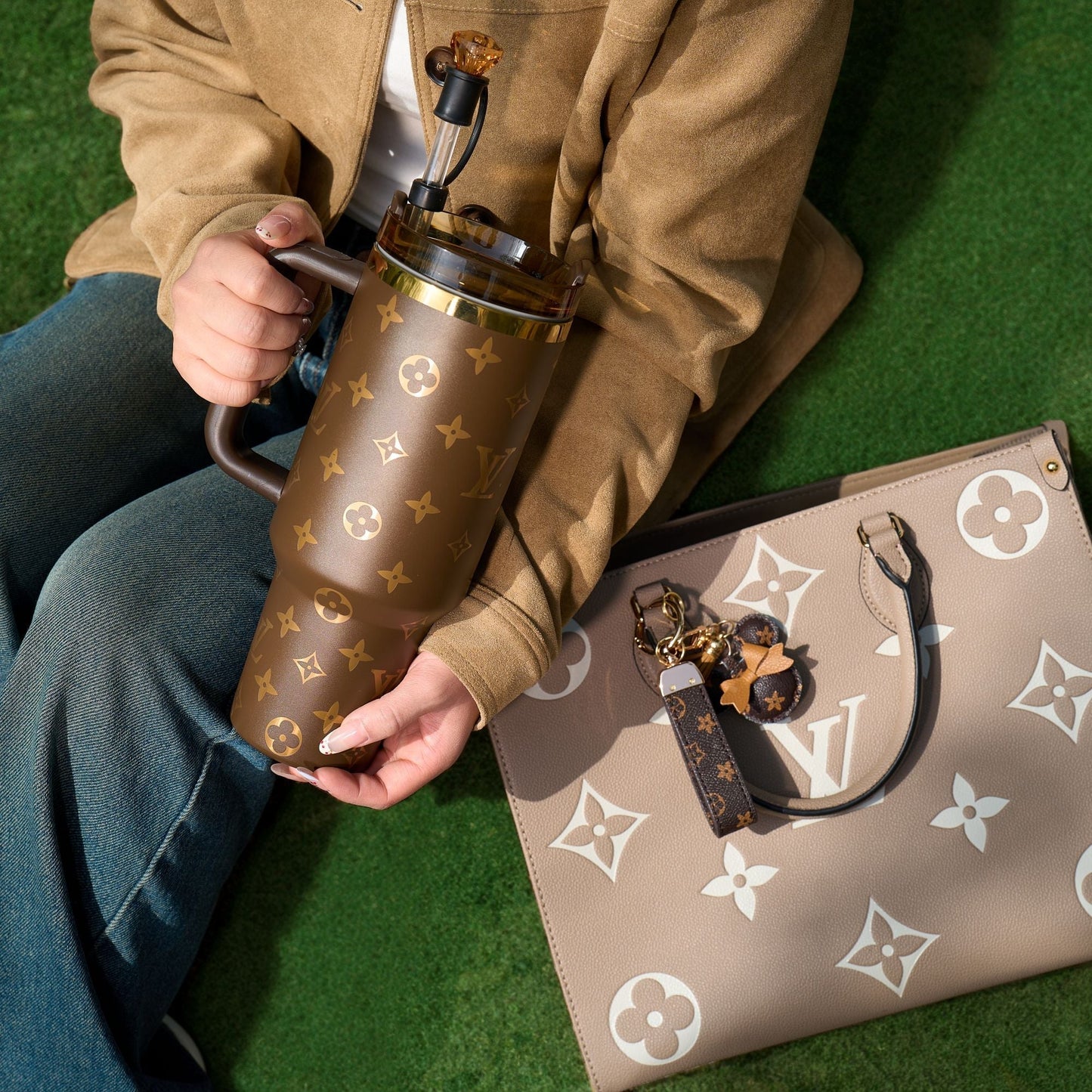 Person holding a brown patterned thermos with a matching handbag on a green surface