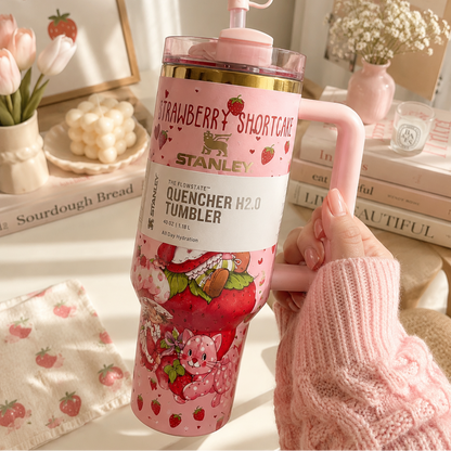 Pink Strawberry Shortcake Stanley tumbler held by a hand with a blurred indoor background