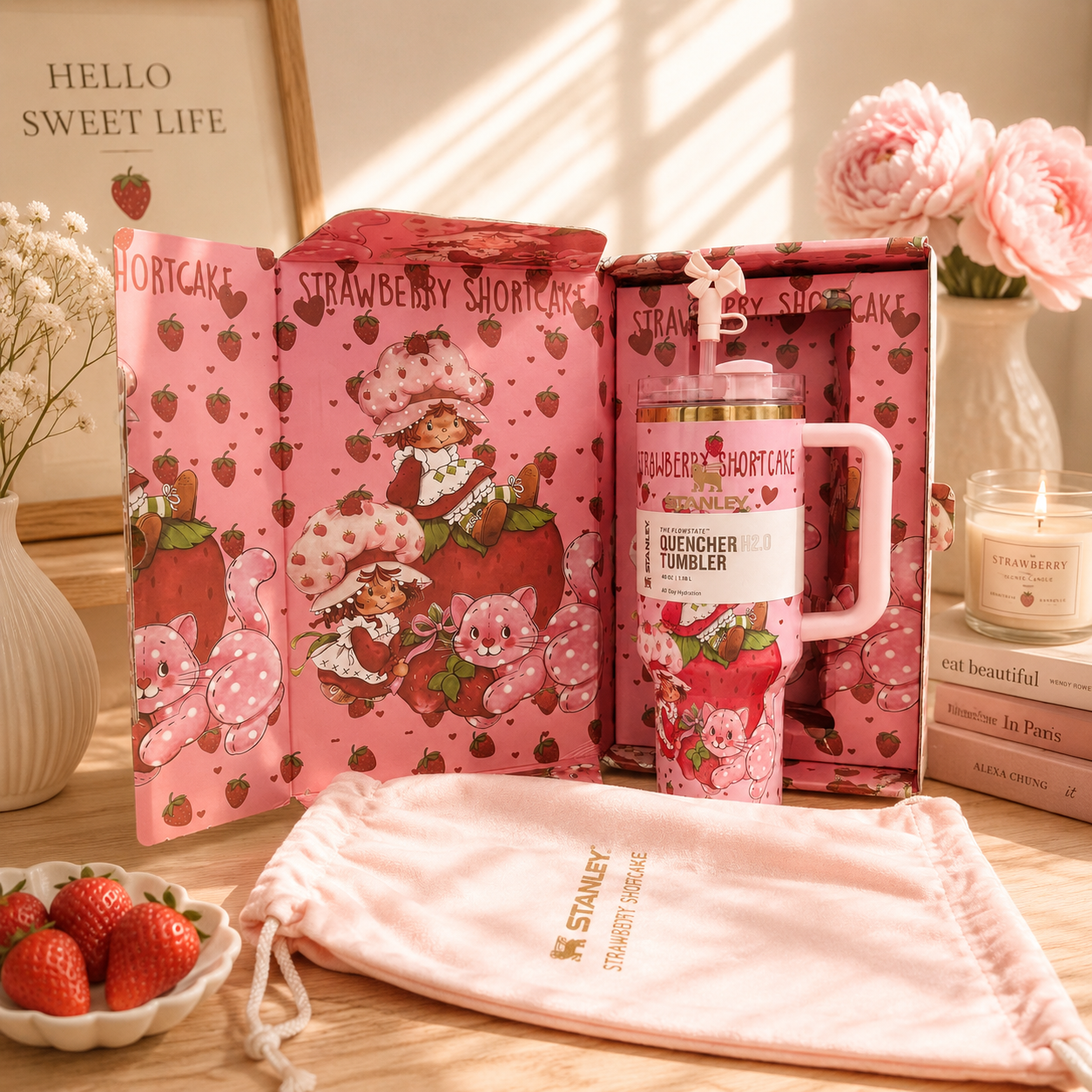 Pink strawberry-themed mug with packaging and decorative elements on a wooden surface.