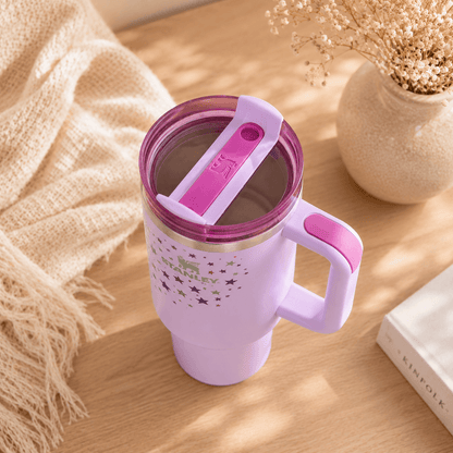 Purple travel mug with pink lid and handle on a wooden surface