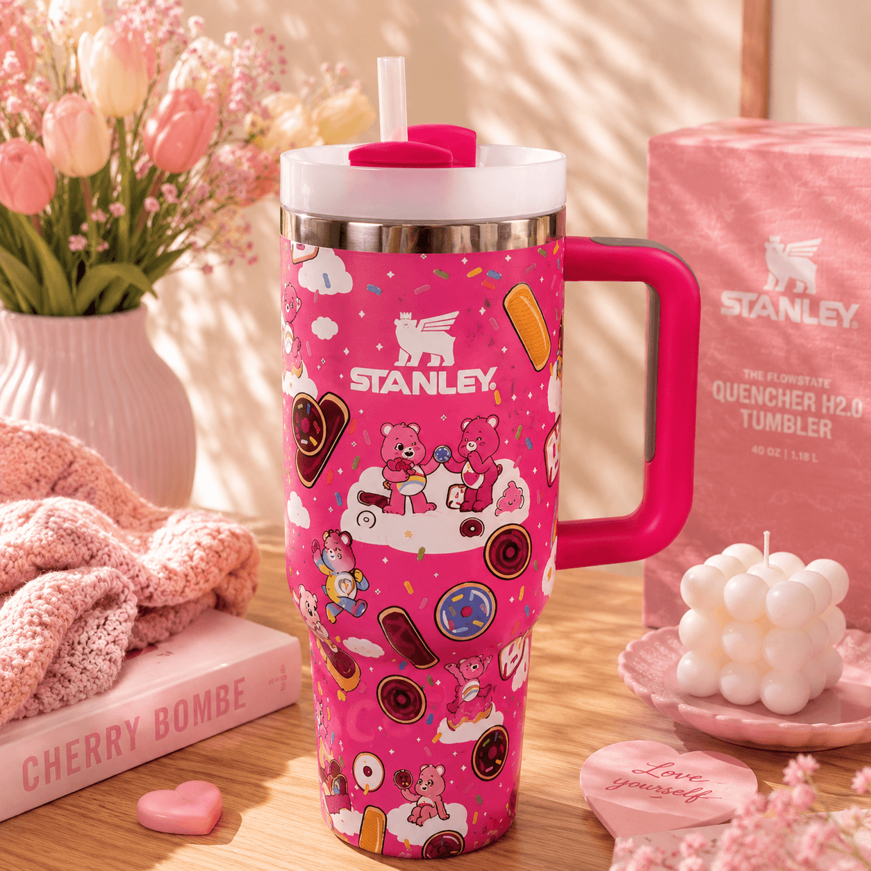 Stanley 40oz insulated tumbler featuring a pink Care Bears-inspired design with donuts, sprinkles, clouds, reusable straw, ergonomic handle, and double-wall vacuum insulation.