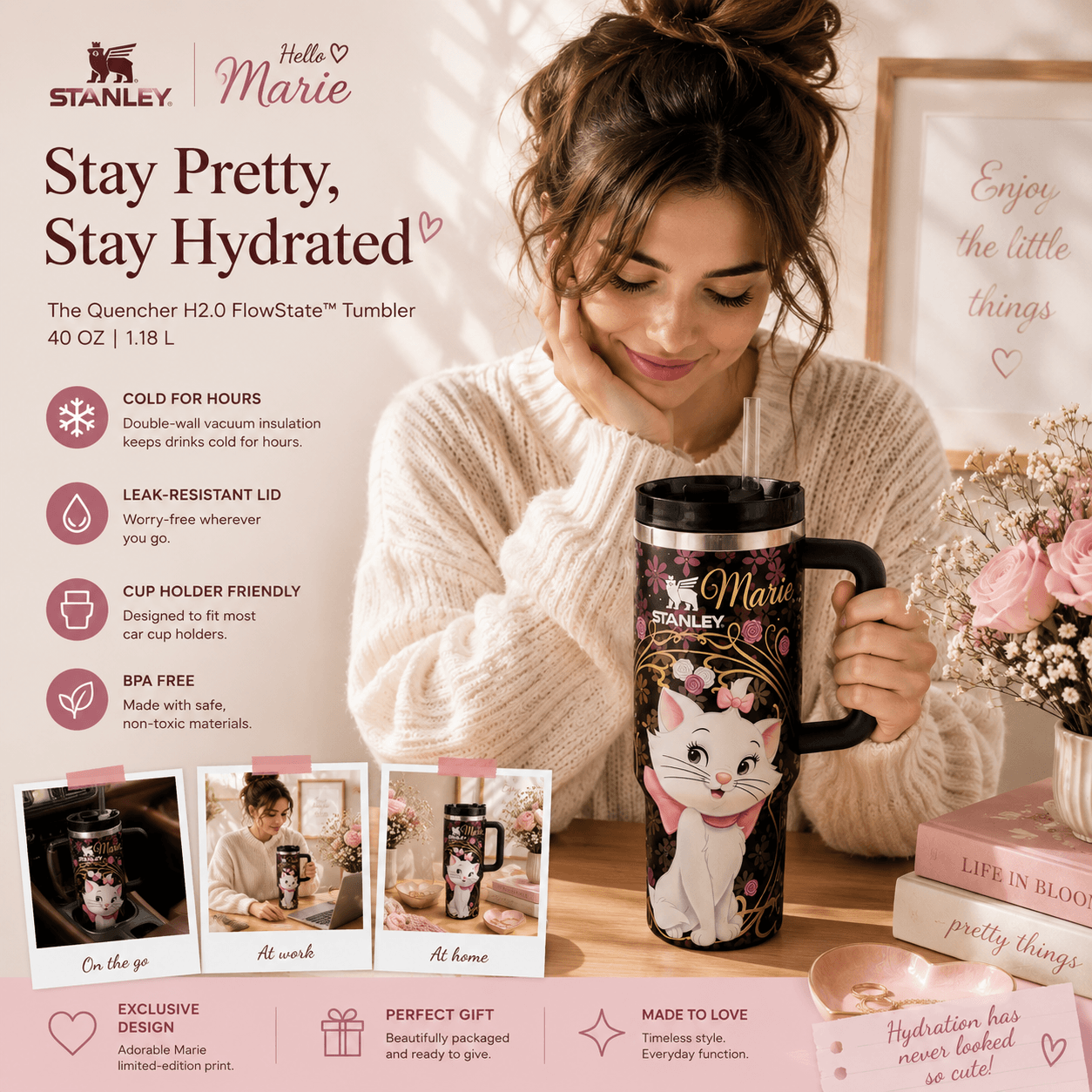 A woman in a cream knit sweater holds a Stanley 'Hello Marie' branded insulated tumbler with a black handle and lid. The scene is a styled indoor setting with pink-toned decor, books, and product callouts on the left.