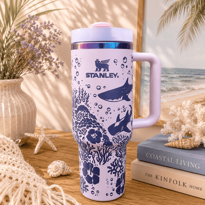 Stanley mug with ocean design on a wooden surface with books and decor