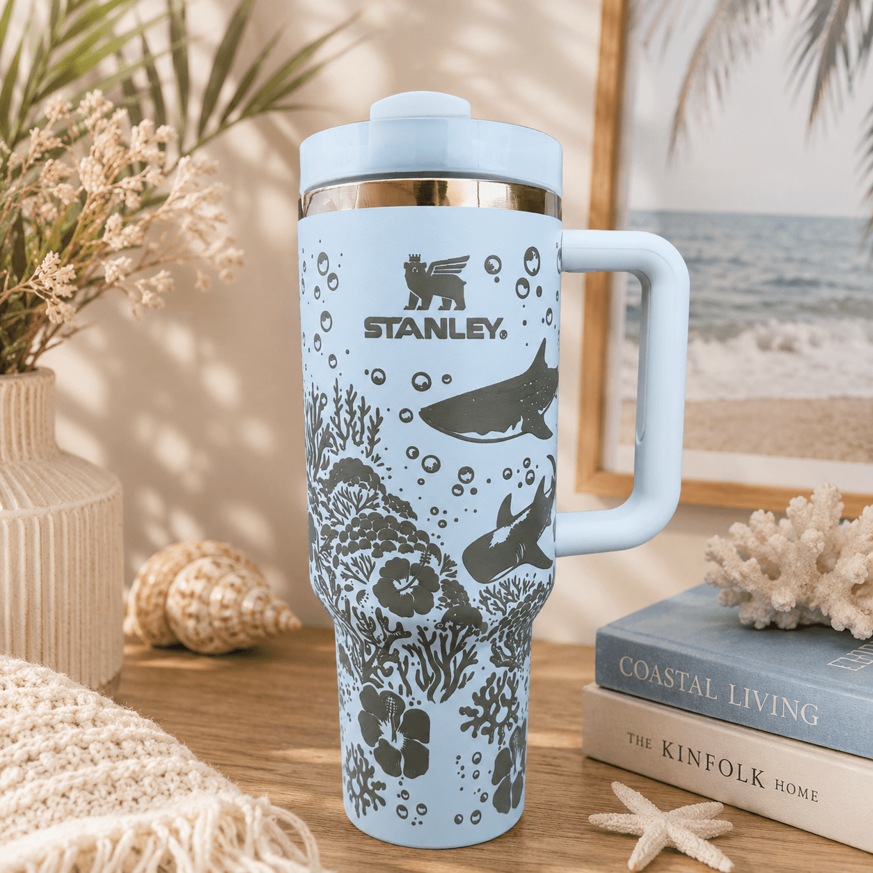 Stanley mug with ocean design on a table with books and decor