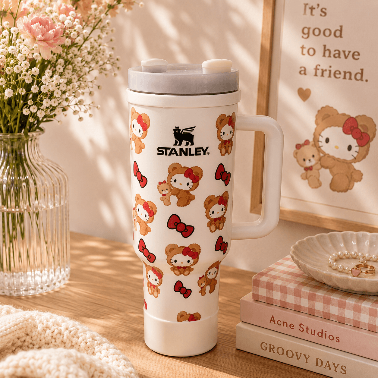 Stanley tumbler with Hello Kitty design on a wooden surface with books and flowers.