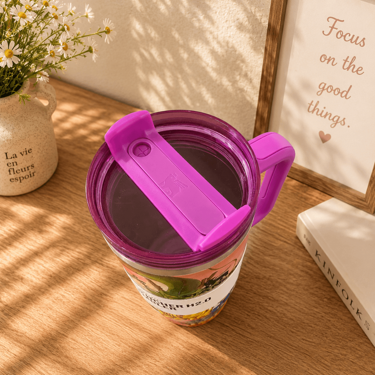Tumbler with purple lid on a wooden surface with decorative elements