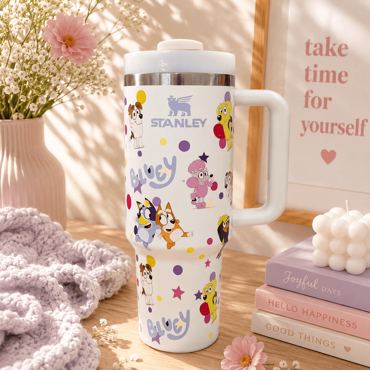 White Stanley 40oz insulated tumbler featuring colorful Bluey-inspired character artwork with ergonomic handle and reusable lid.