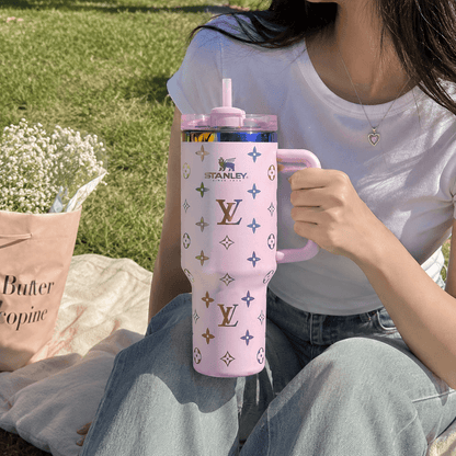 Person holding a pink Stanley tumbler with a pattern outdoors
