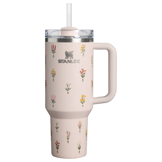 Stanley 40oz insulated tumbler featuring delicate wildflower illustrations, soft blush pink finish, white ergonomic handle, and insulated design